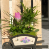 Carretilla Floral Artesanal con flores naturales y plantas ornamentales sobre fondo rústico de madera – Floristería Sayde en Zaragoza.
