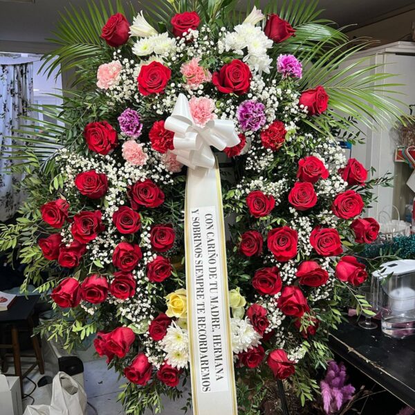 Corona funeraria en Zaragoza con rosas rojas, flores blancas y follaje verde - Floristería Sayde.