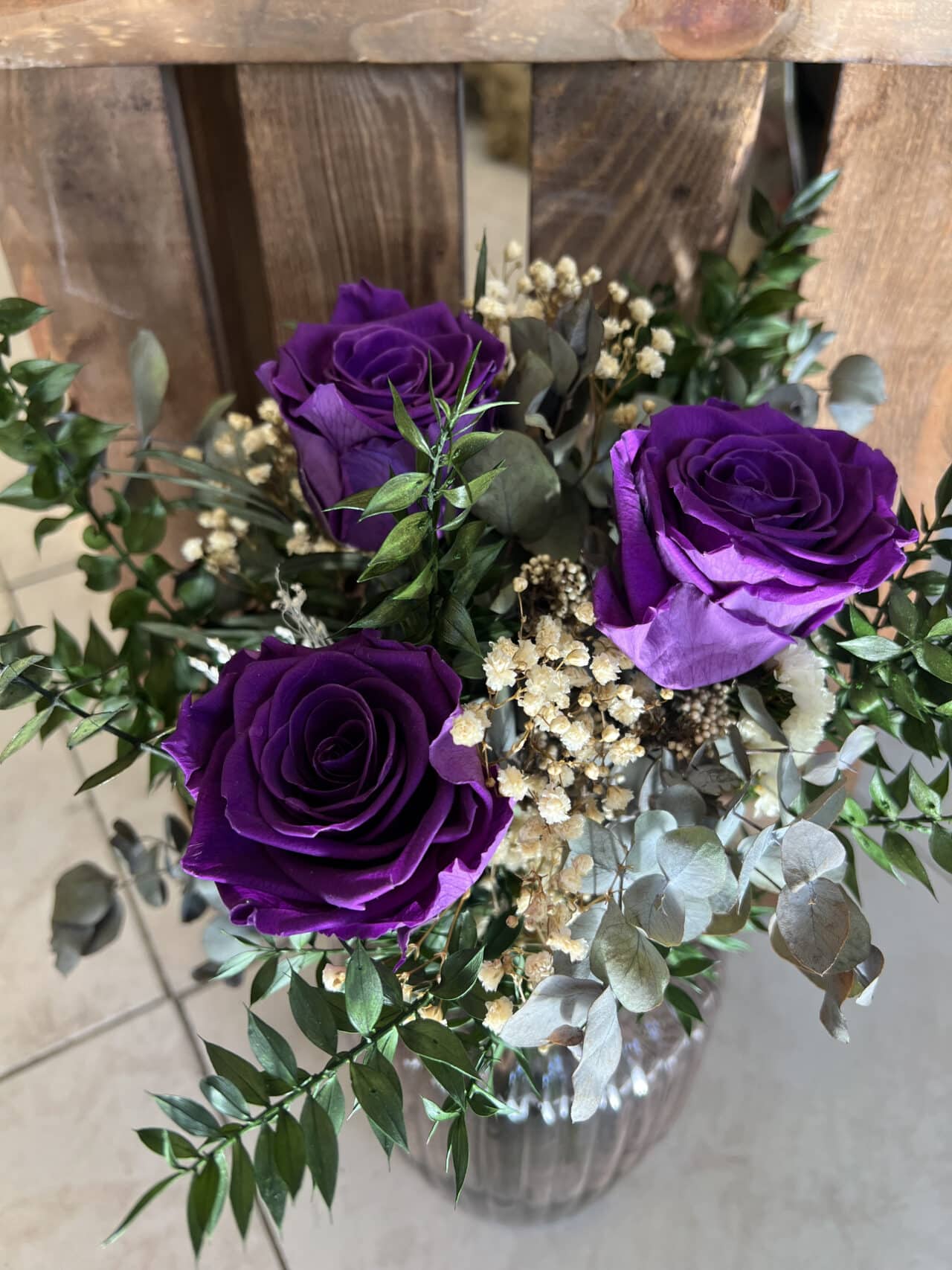 Ramo Preservado de Rosas Violetas en jarrón de vidrio, con hojas de eucalipto y flores secas, disponible en Floristería Sayde, Zaragoza. Diseño elegante y duradero.