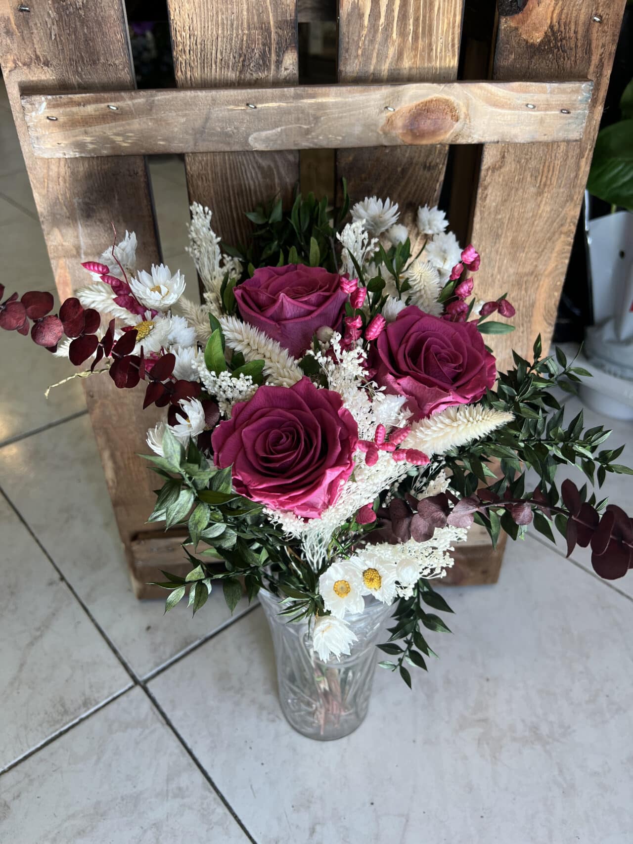 Ramo Preservado de Rosas Fucsia con follaje verde, flores secas en tonos crema y burdeos, acompañado de un jarrón decorativo de vidrio. Creación exclusiva de Floristería Sayde, Zaragoza.